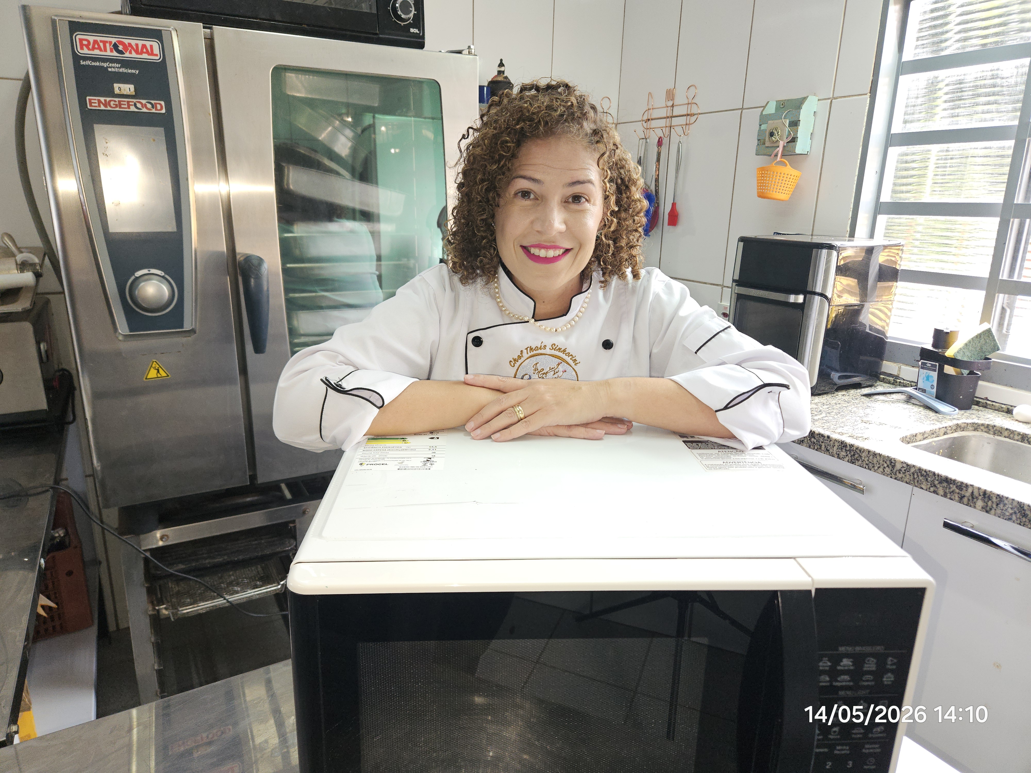 Chef Thaís Sinhorini na cozinha profissional com micro-ondas